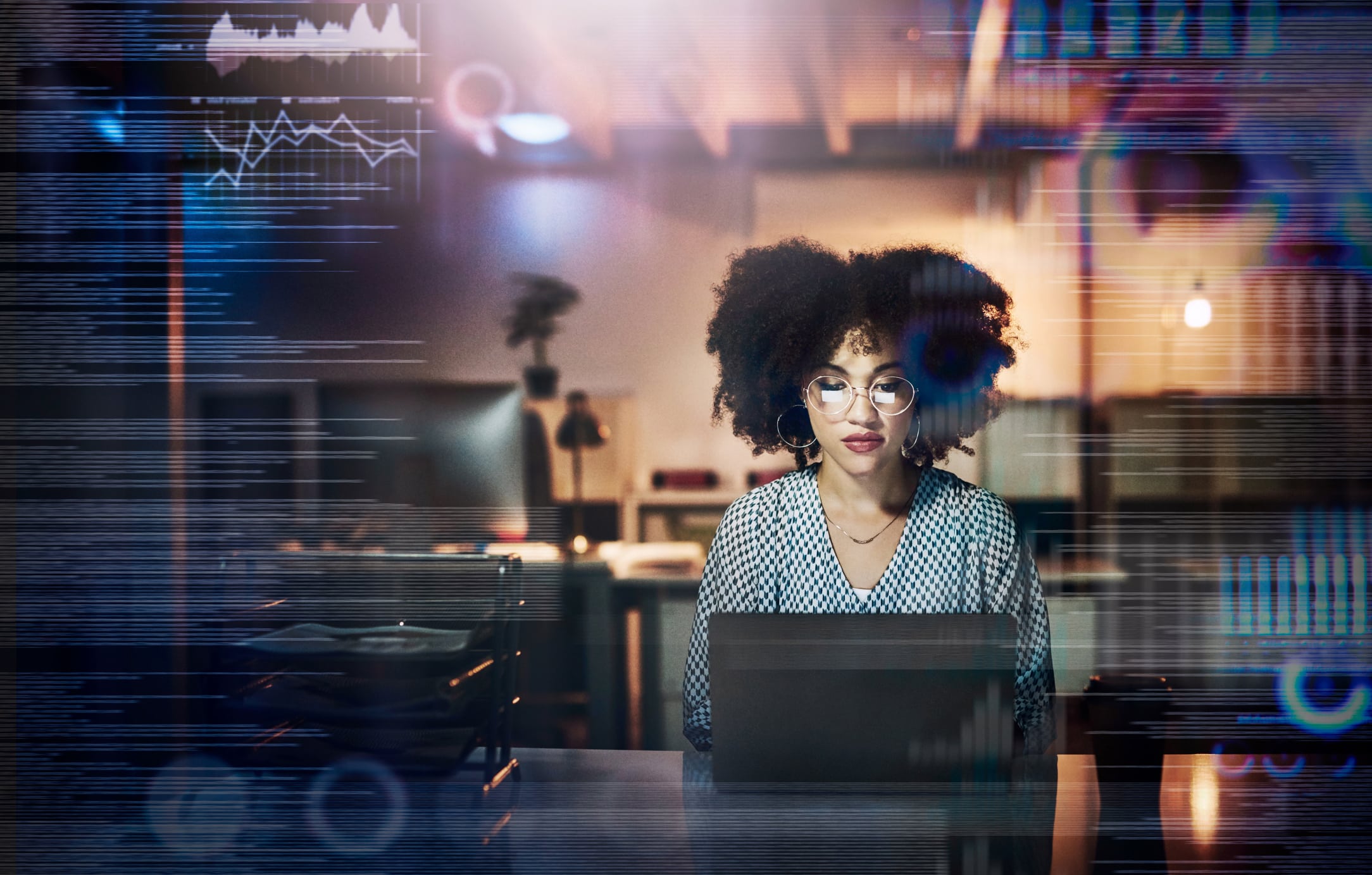 Shot of a young female programmer using a laptop while working late in her office